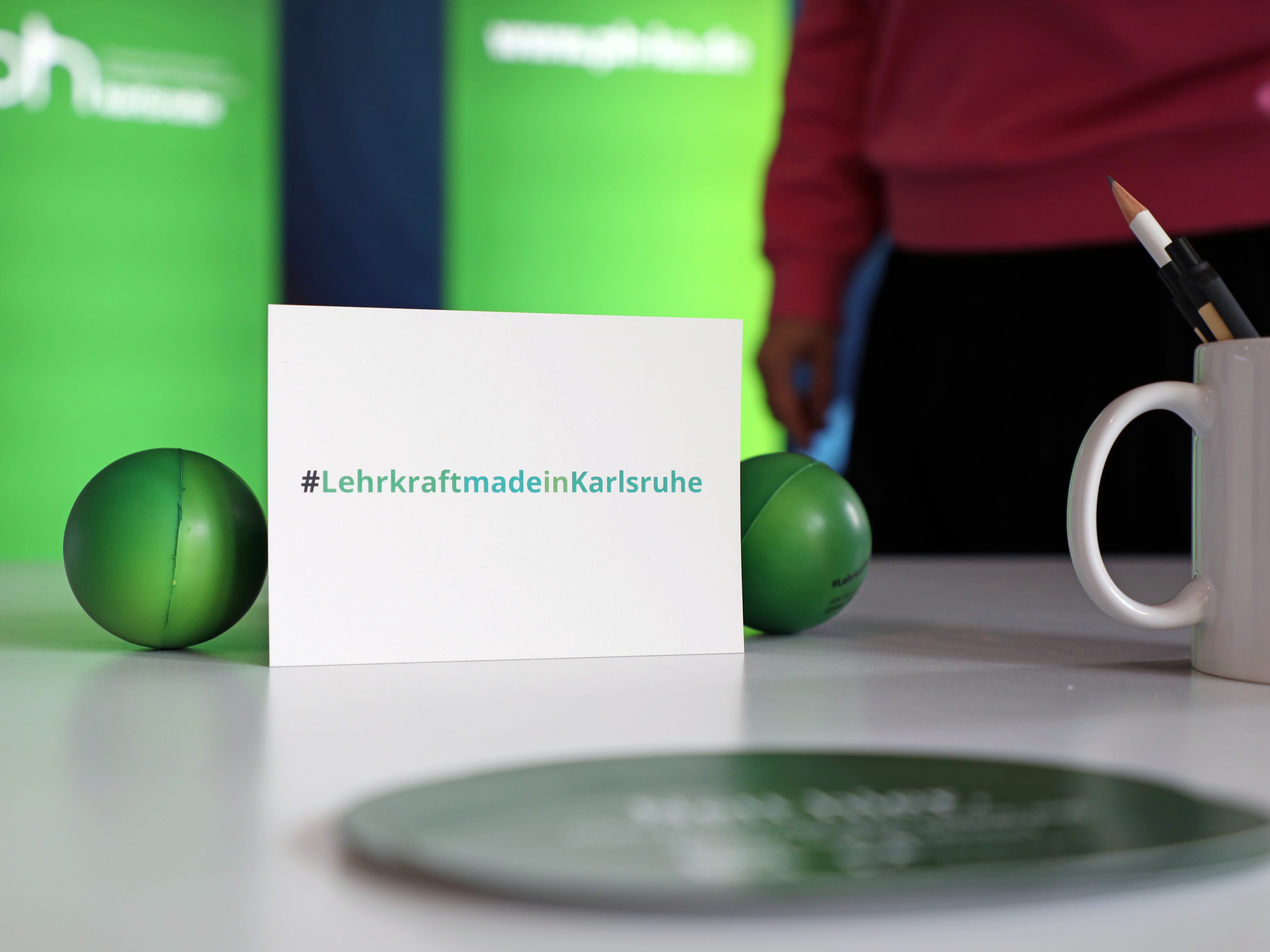 Eine Postkarte lehnt auf einer Tischplatte mit dem Aufdruck hashtag LehrkraftmadeinKarlsruhe