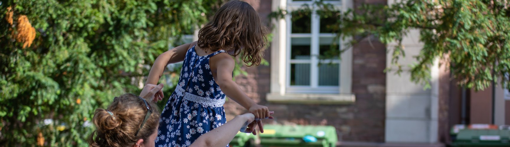 eine junge Frau spielt mit ihrer Tochter auf dem Campus