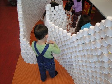 Ein kleiner Junge stapelt leere Eisbecher zu einer Mauer