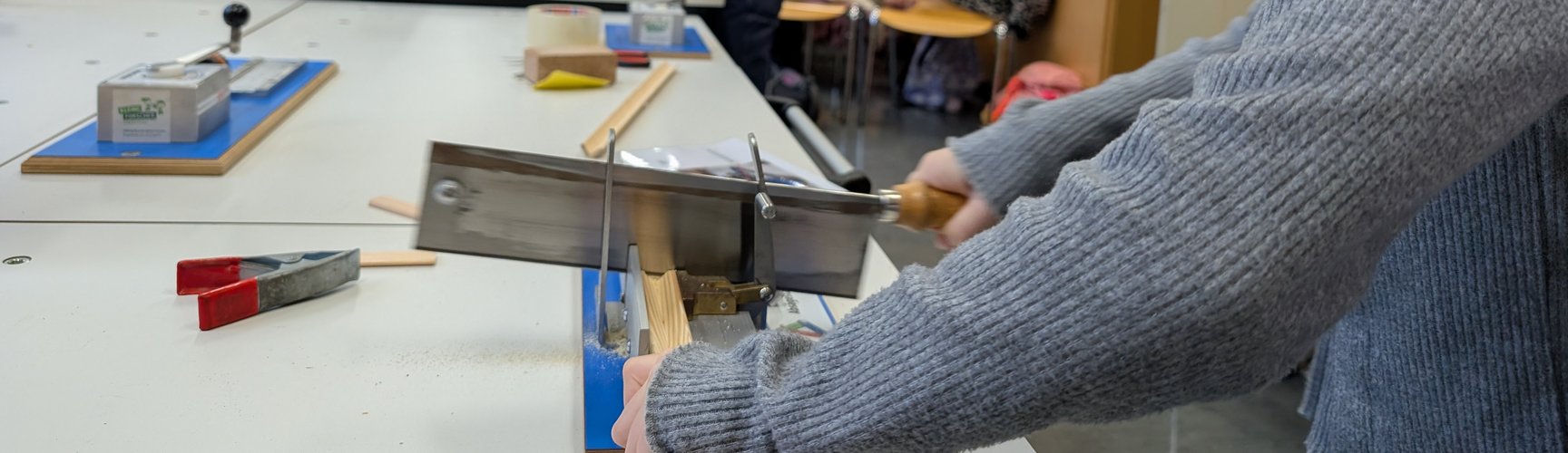 Ein Mädchen arbeitet mit einer Säge an einem Werktisch