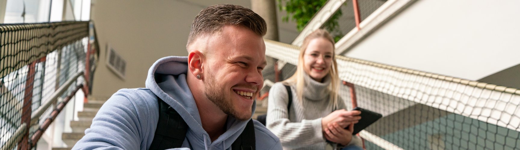 Zwei Studierende sitzen auf einer Treppe