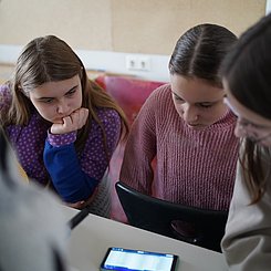 zu sehen sind Schülerinnen, die das Co2-Messgerät betrachten.