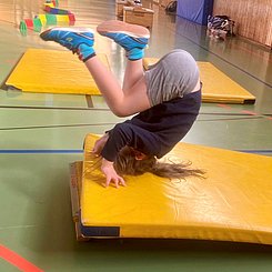Ein Kind macht einen Purzelbaum auf einer Turnmatte 