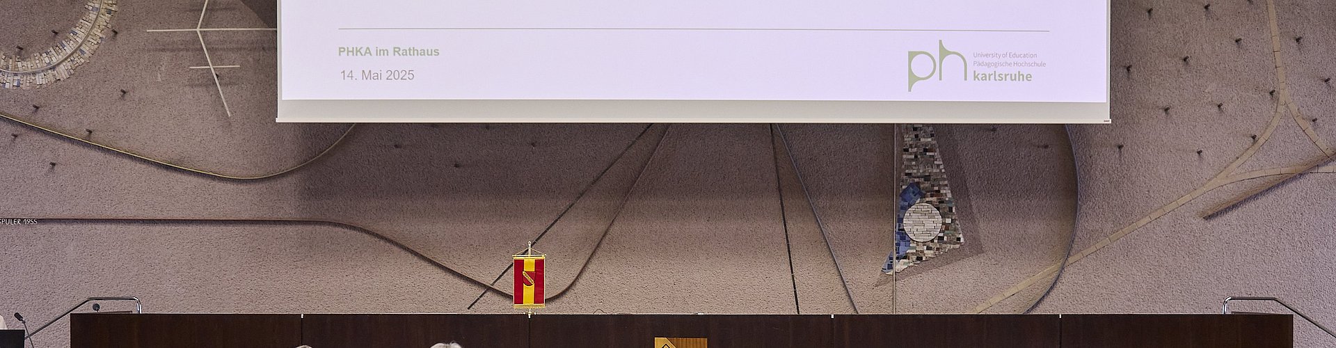 Publikum von hinten im Bürgersaal der Stadt Karlsruhe mit Blick auf Pul und Leinwand